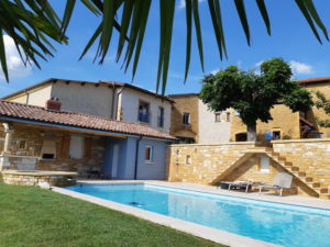 Piscine avec vue du gîte en arrière plan à gauche mitoyen à la maison des propriétaires.